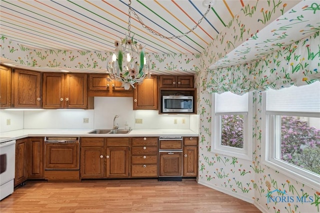 kitchen with wallpapered walls, brown cabinets, a sink, and stainless steel microwave