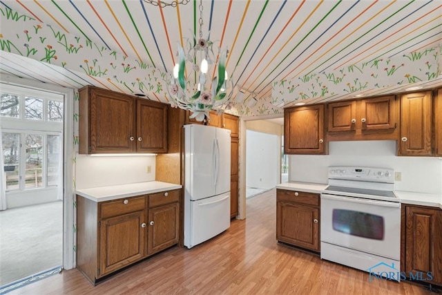 kitchen featuring vaulted ceiling, wallpapered walls, white appliances, and light countertops