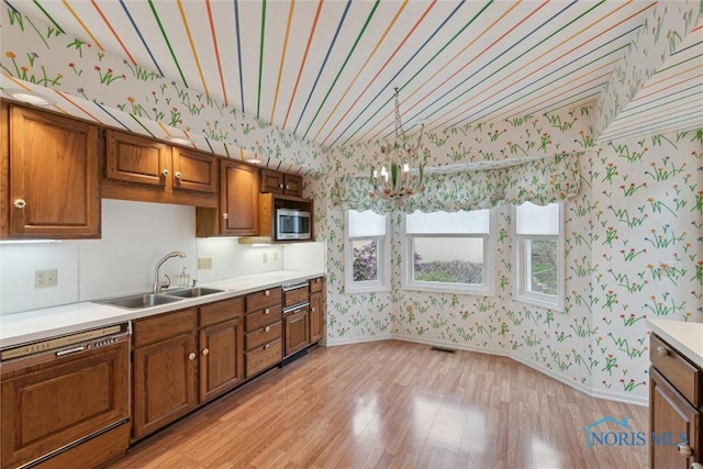 kitchen featuring light wood finished floors, a sink, stainless steel microwave, wallpapered walls, and dishwasher