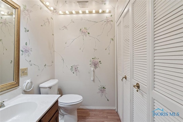 bathroom with toilet, visible vents, wood finished floors, a closet, and vanity