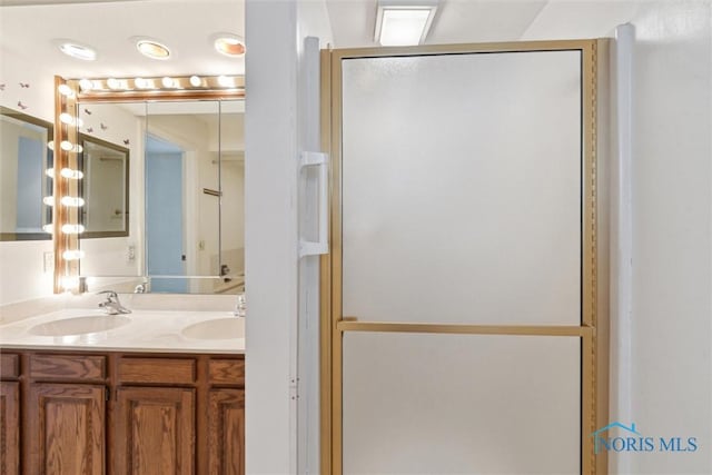 bathroom with double vanity, a stall shower, and a sink