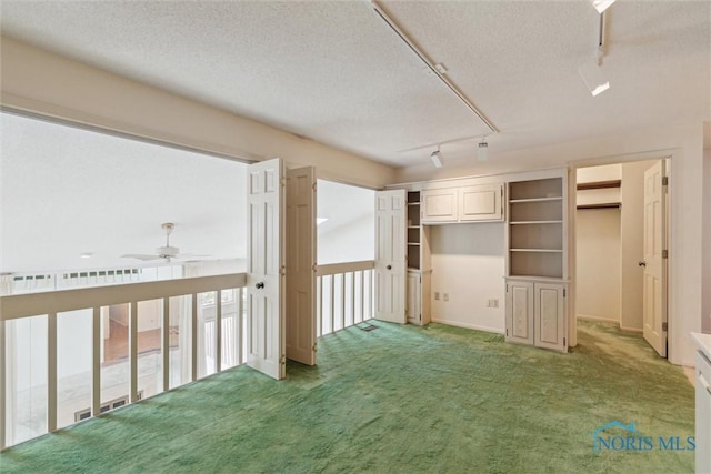 interior space featuring track lighting, a textured ceiling, and light carpet