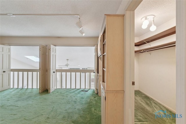 interior space featuring track lighting, carpet flooring, and a textured ceiling