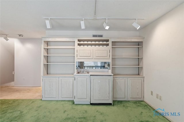 bar featuring rail lighting, baseboards, light carpet, and visible vents