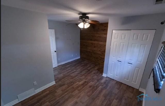 3844 Washburn Rd, Berkey, OH 43504 - unfurnished bedroom with baseboards, wood finished floors, a closet, wood walls, and a ceiling fan