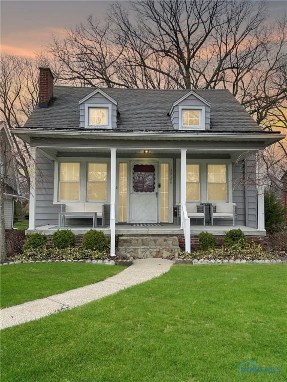 view of front of property featuring a chimney, a front lawn, and covered porch