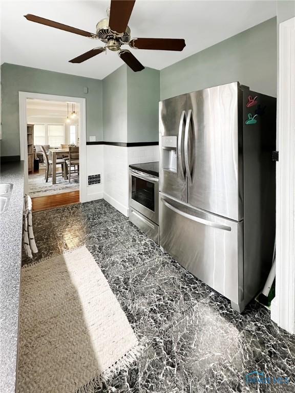 kitchen with appliances with stainless steel finishes, ceiling fan, baseboards, and visible vents
