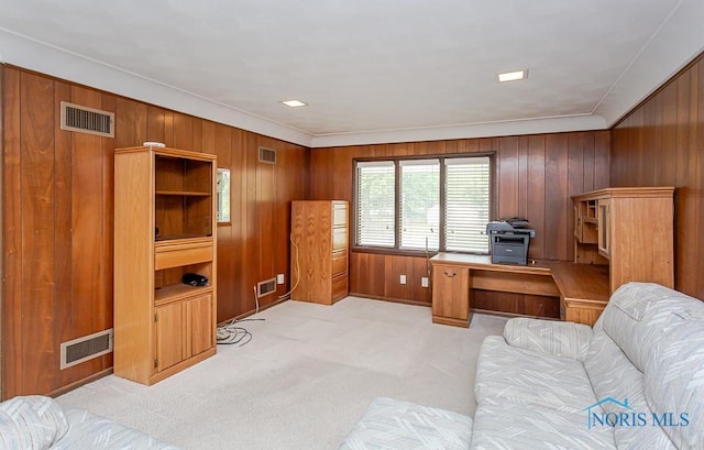 office space with light carpet, visible vents, and wooden walls