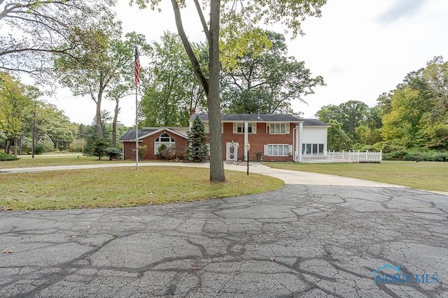 split foyer home with brick siding, a front yard, and driveway