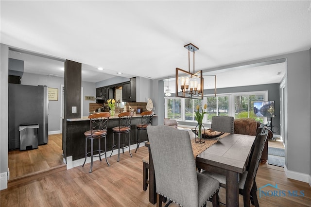 dining room with light wood-style flooring, an inviting chandelier, baseboards, and recessed lighting