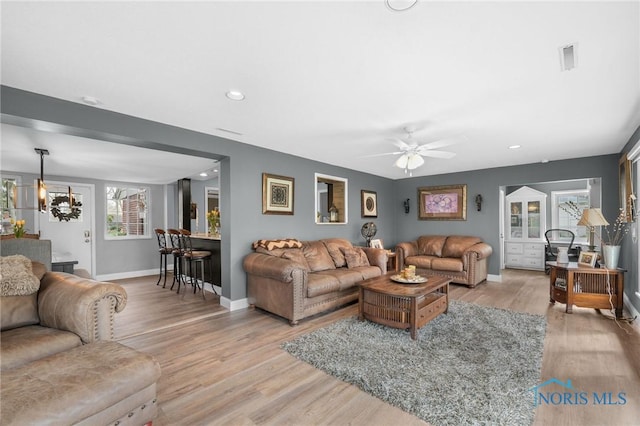 living area with visible vents, ceiling fan, light wood-type flooring, and baseboards