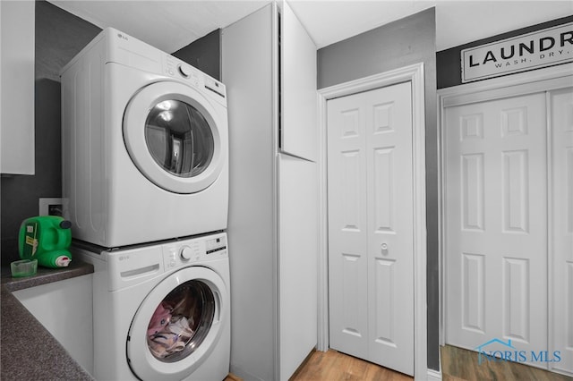 laundry room featuring light wood-type flooring, stacked washer and dryer, and laundry area
