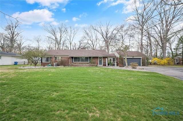 ranch-style home with brick siding, a front lawn, a garage, and driveway