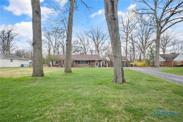 single story home featuring a front yard, brick siding, and driveway