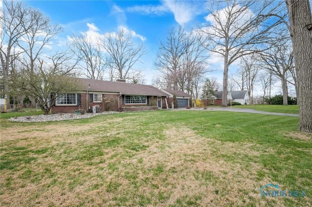 ranch-style house with aphalt driveway, a front lawn, brick siding, a chimney, and a garage
