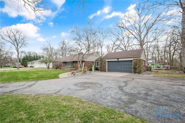view of front of home featuring an attached garage, aphalt driveway, a front lawn, and brick siding