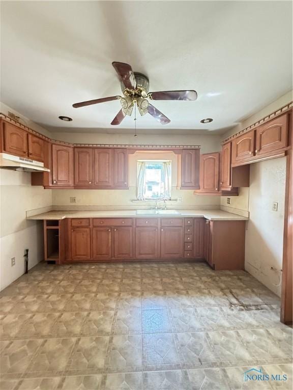 129 Everett St, Toledo, OH 43608 - kitchen featuring under cabinet range hood, ceiling fan, brown cabinets, and light countertops