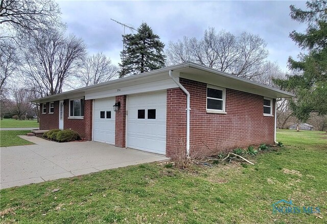 354 N River Rd, Waterville, OH 43566 - view of property exterior with concrete driveway, a garage, brick siding, and a yard