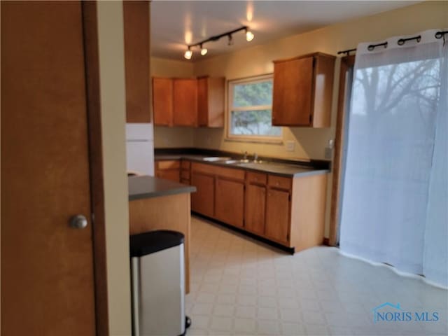 354 N River Rd, Waterville, OH 43566 - kitchen featuring rail lighting, dark countertops, light floors, a sink, and brown cabinetry