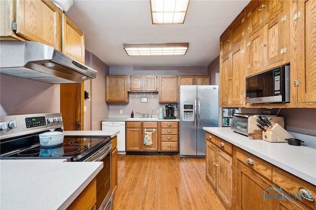kitchen with light countertops, stainless steel appliances, a sink, light wood-type flooring, and ventilation hood