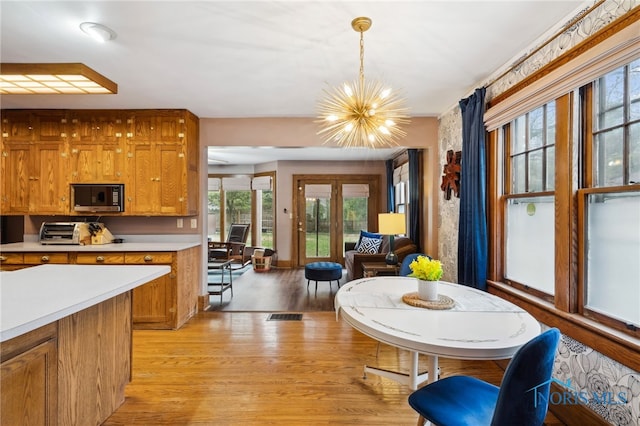 dining space with light wood finished floors, a chandelier, and a toaster
