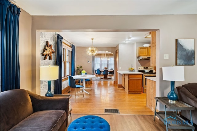 living area featuring an inviting chandelier, light wood-style flooring, baseboards, and visible vents