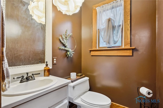 bathroom featuring toilet, vanity, and a notable chandelier