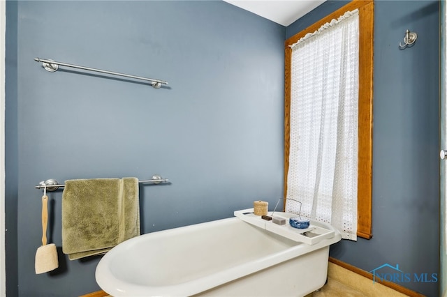 bathroom featuring baseboards and a soaking tub