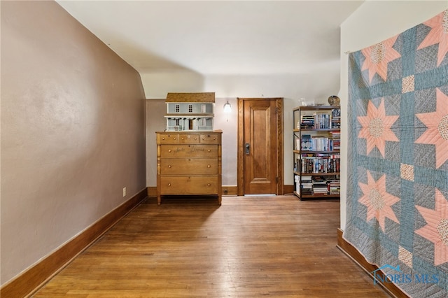 hall with baseboards and wood finished floors