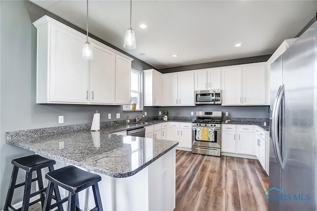 100 Bentley Dr, Perrysburg, OH 43551 - kitchen with a peninsula, wood finished floors, appliances with stainless steel finishes, dark stone countertops, and white cabinetry