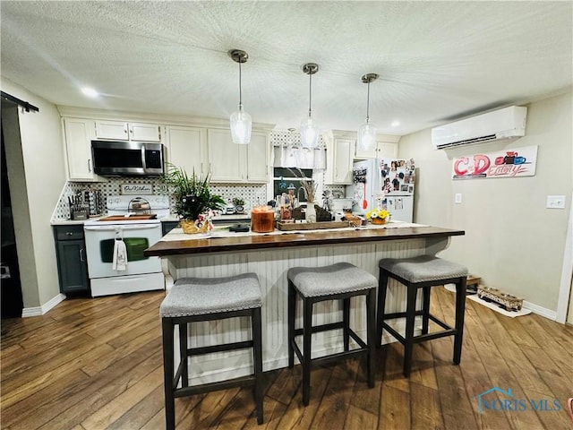 kitchen featuring a wall mounted AC, backsplash, a kitchen breakfast bar, white appliances, and dark wood-type flooring