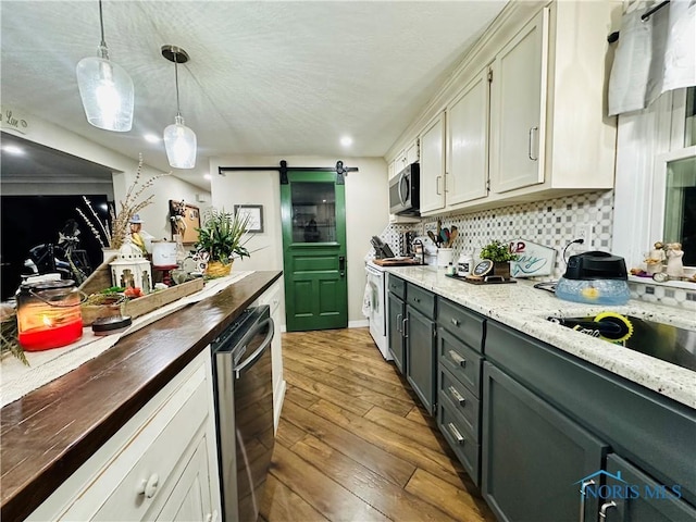 kitchen featuring stainless steel microwave, backsplash, hardwood / wood-style flooring, a barn door, and white electric range
