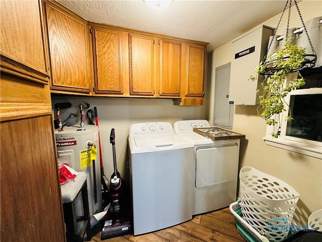 laundry area featuring a textured ceiling, independent washer and dryer, wood finished floors, water heater, and cabinet space