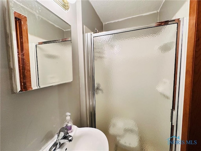bathroom with a textured ceiling and a shower stall