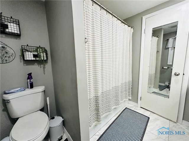 full bath featuring baseboards, marble finish floor, toilet, and a shower with shower curtain