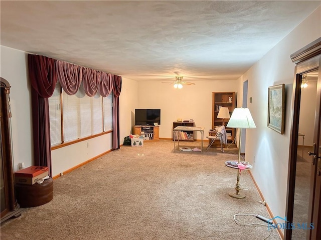 interior space with carpet floors, baseboards, and ceiling fan