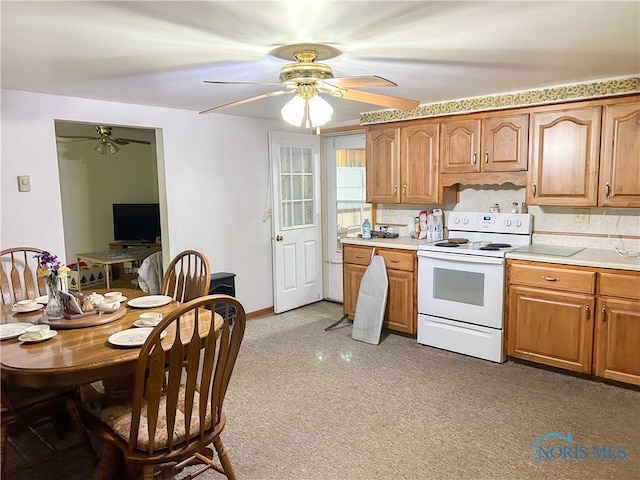 kitchen with white electric range oven, brown cabinets, ceiling fan, and light countertops