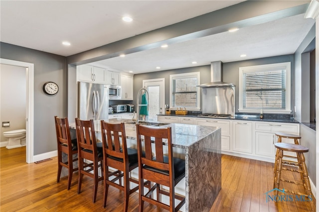 3114 Gleneagle Dr, Findlay, OH 45840 - kitchen with wall chimney range hood, white cabinetry, a sink, light wood-style flooring, and appliances with stainless steel finishes