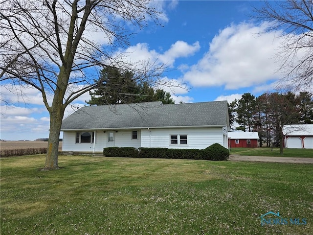 view of front facade featuring driveway, a garage, roof with shingles, and a front yard