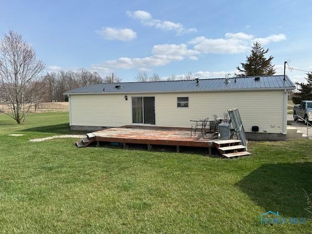 rear view of property with metal roof, a wooden deck, and a yard