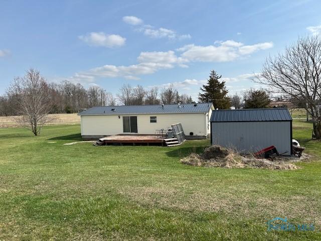 back of property featuring a yard, metal roof, an outdoor structure, and a deck