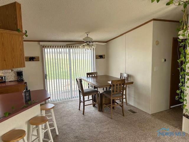 dining area with carpet floors, ornamental molding, visible vents, and ceiling fan