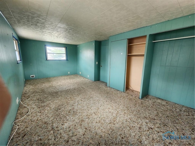 825 Park St, Findlay, OH 45840 - unfurnished bedroom featuring multiple closets, wood walls, and carpet flooring