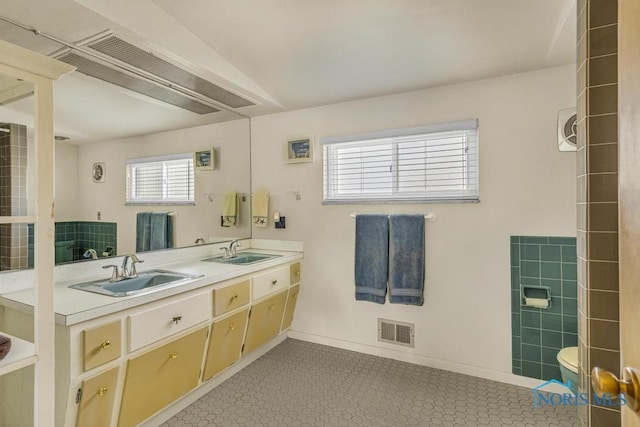 bathroom featuring a sink, double vanity, visible vents, and toilet
