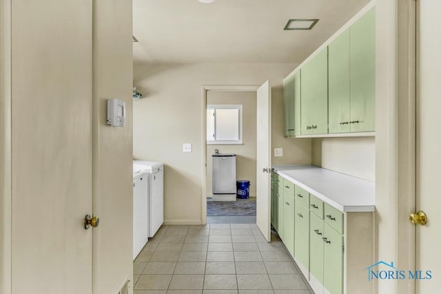 kitchen with green cabinets, light countertops, washer and clothes dryer, and light tile patterned floors