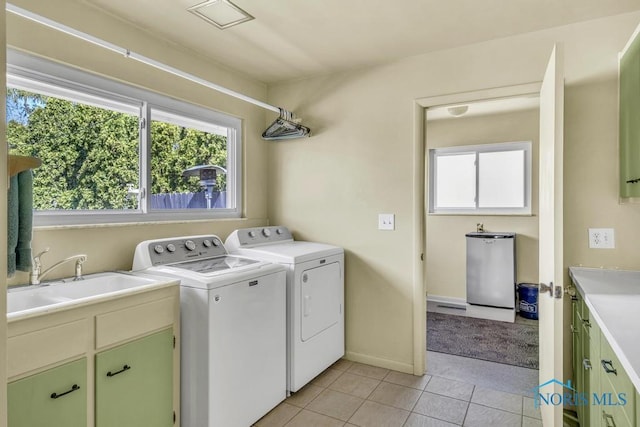 washroom featuring a sink, light tile patterned floors, baseboards, washer and dryer, and cabinet space