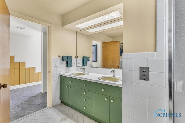 full bathroom with tile walls, visible vents, double vanity, and a sink