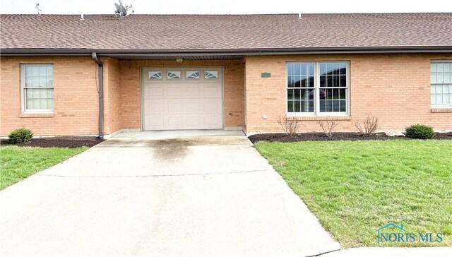 12783 Rd 82 Unit 1, Paulding, OH 45879 - property entrance with a garage, brick siding, roof with shingles, driveway, and a yard