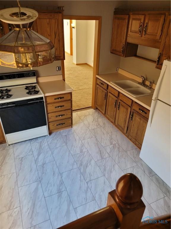 621 Nevada St, Toledo, OH 43605 - kitchen featuring light countertops, a sink, brown cabinets, marble finish floor, and white appliances
