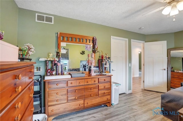 bedroom featuring visible vents, a ceiling fan, light wood-type flooring, and a textured ceiling